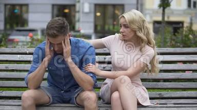 担心的家伙坐在长凳上，女朋友让他冷静下来，问题，支持